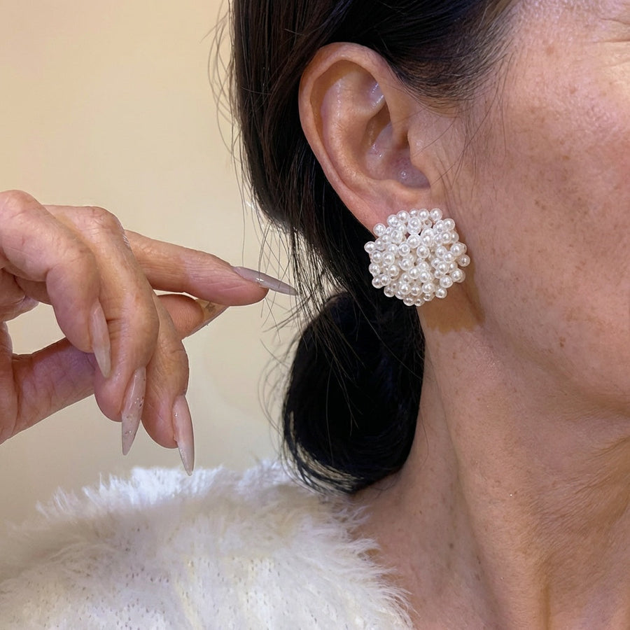 Round inlaid pearl cluster earrings worn on ear, white beads on metal setting