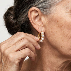 Gold hoop earrings with white pearl cluster on earlobe