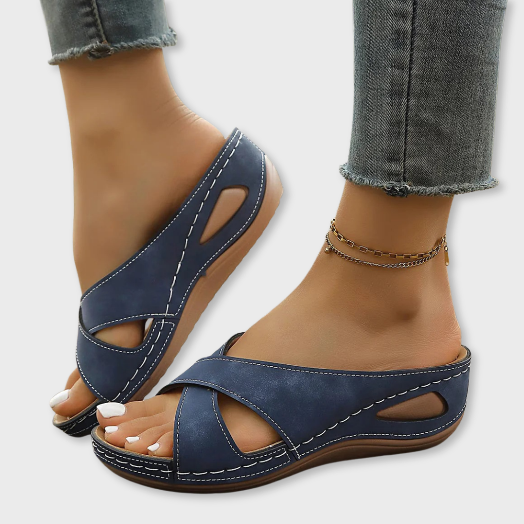 Blue open-toe slide sandals with cross straps, stitched sole, and ankle chain strap